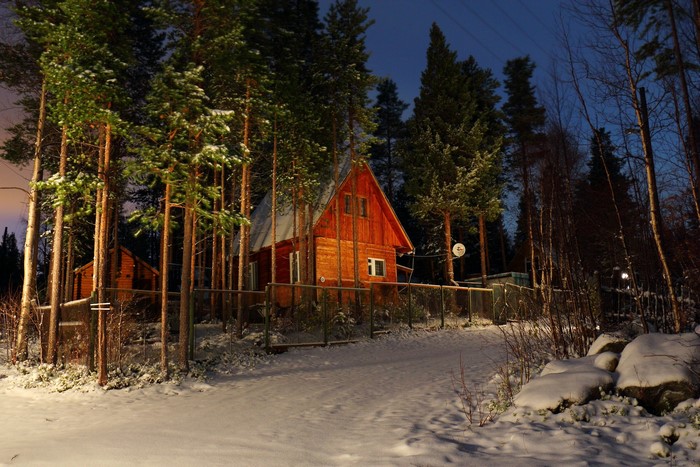 Wooden house in a snowy forest at night
