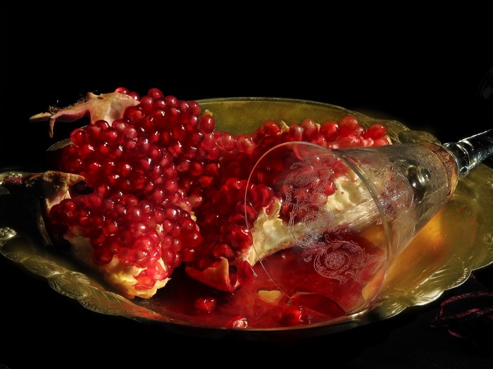 Pomegranate on a decorative plate with a glass