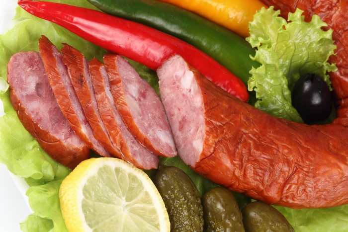 Sliced sausage with chili peppers, lemon, and pickles