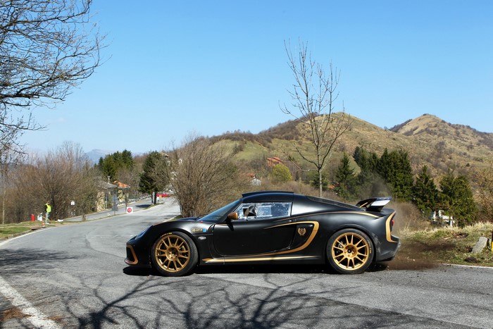 Black Lotus Exige R-GT with gold accents on a mountain road