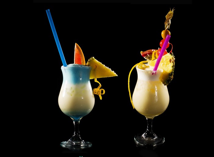 Two tropical cocktails with fruit garnishes