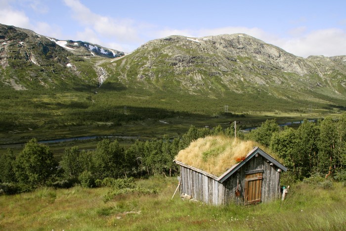 Small wooden cabin with grass roof in a Norwegian valley