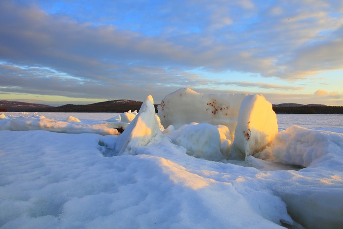 Ice formations on a frozen lake at sunset