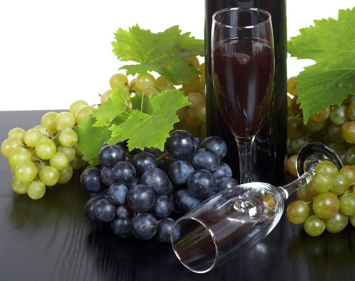 Grapes and wine with stemware on a dark surface