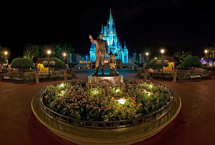 Walt Disney and Mickey Mouse statue in front of Cinderella Castle at night