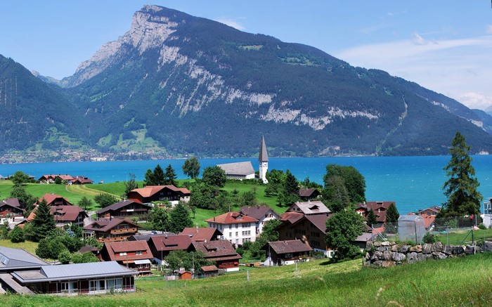 Village with church by a lake and mountains in Switzerland