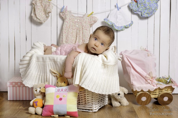 Baby in a basket with toys and clothes