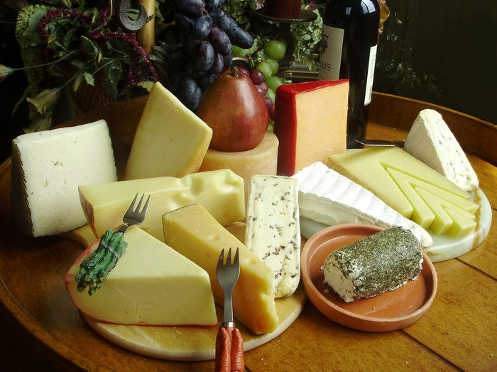 Assortment of cheeses with forks and grapes