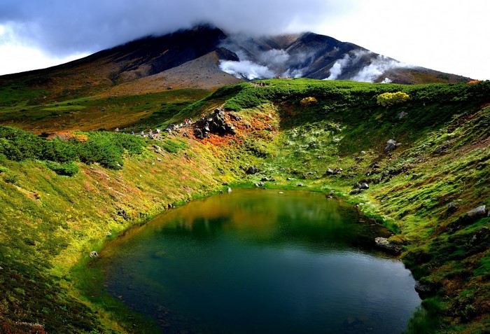 Volcanic crater lake with steam vents and a mountain in Hokkaido, Japan