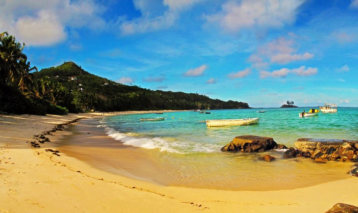 Tropical beach with boats and lush green hill