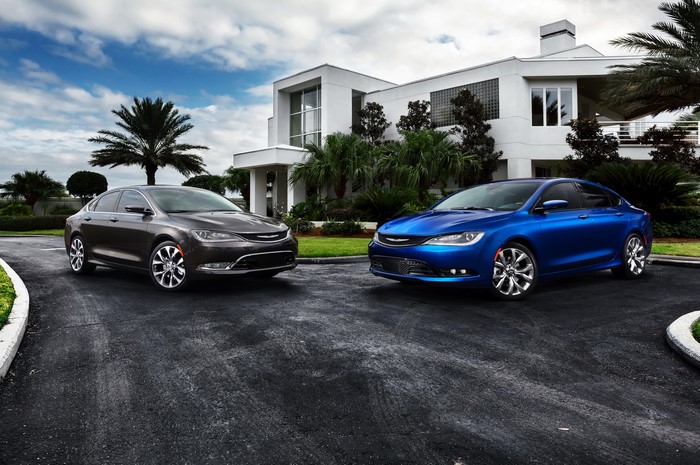 Two Chrysler 200 sedans parked in front of a modern house