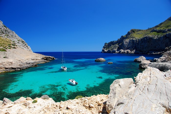 Sailboat and motorboat in a turquoise cove in Majorca, Spain