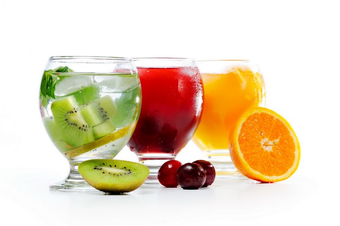 Three glasses of juice with kiwi, cherry, and orange