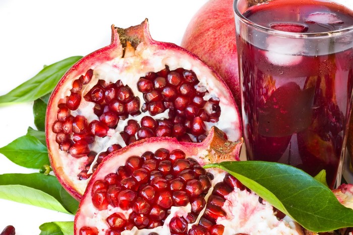Pomegranate juice with fresh pomegranates and leaves
