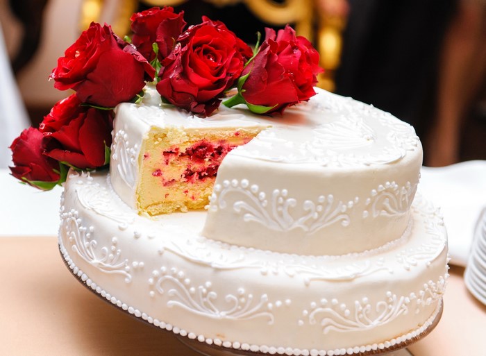 Two-tiered white cake with red roses and raspberry filling