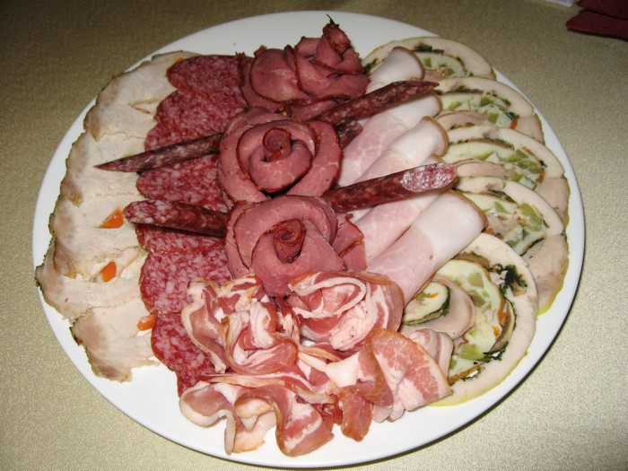 Assortment of cured meats and rolls on a white plate