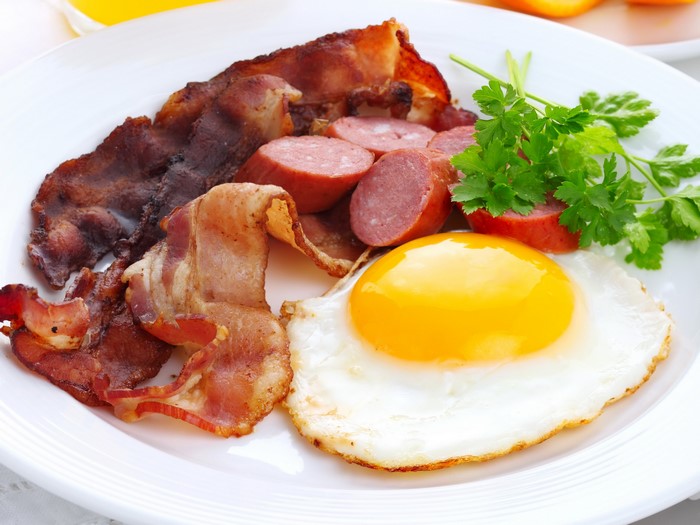 Fried egg with bacon and sausages on a plate