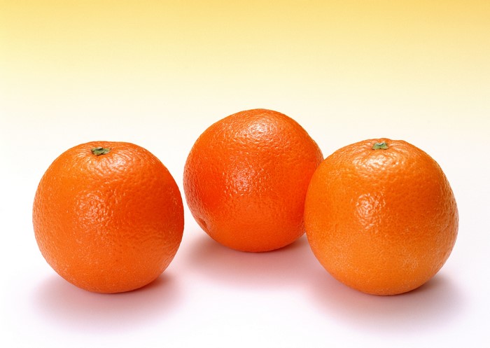 Three oranges on a white surface