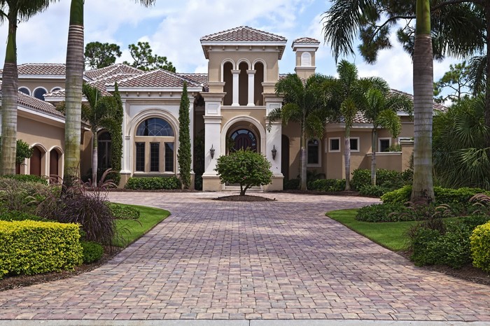 Luxury mansion with palm trees and paved driveway