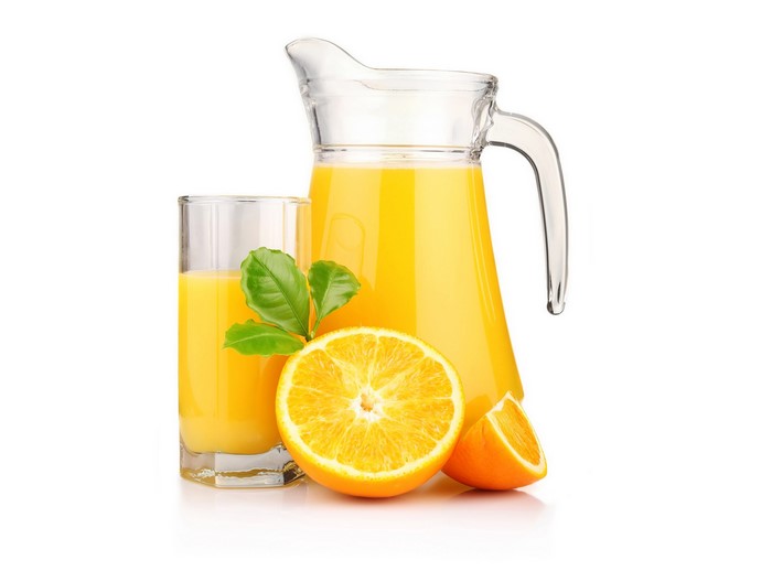 Orange juice in a glass and pitcher with oranges