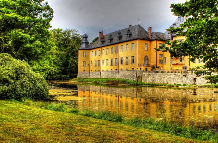 Yellow castle reflected in a pond in Dyck, Germany
