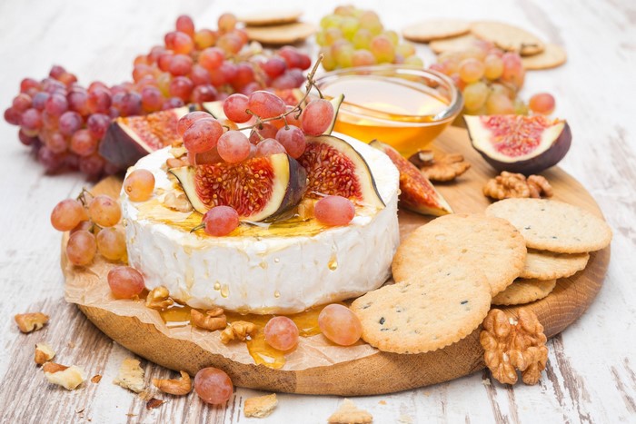 Cheese board with grapes, figs, honey, and crackers