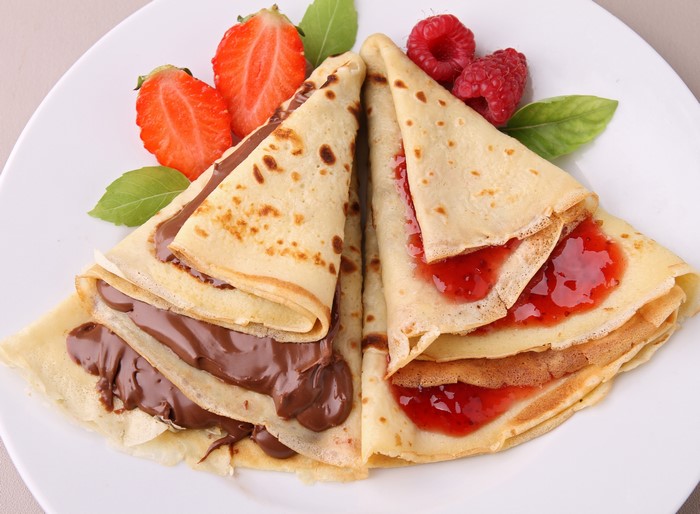 Crepes with chocolate spread and strawberry jam on a plate