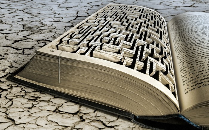Book with maze carved into pages on cracked ground