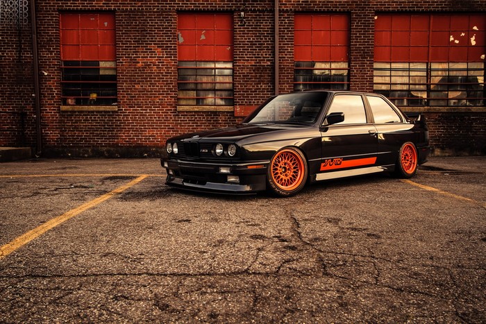 Tuned black BMW E30 M3 with orange wheels
