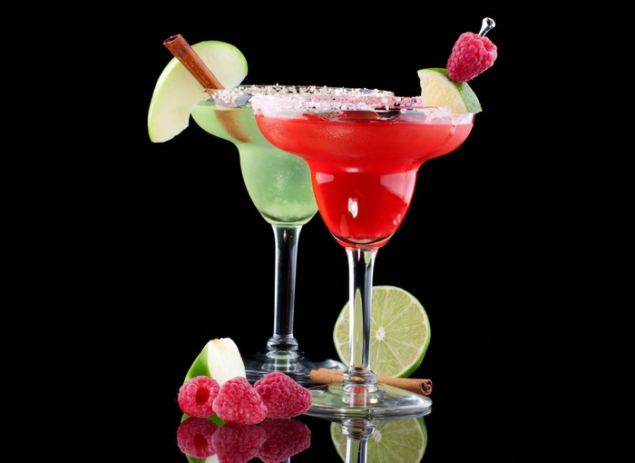 Two cocktails with fruit and cinnamon garnish