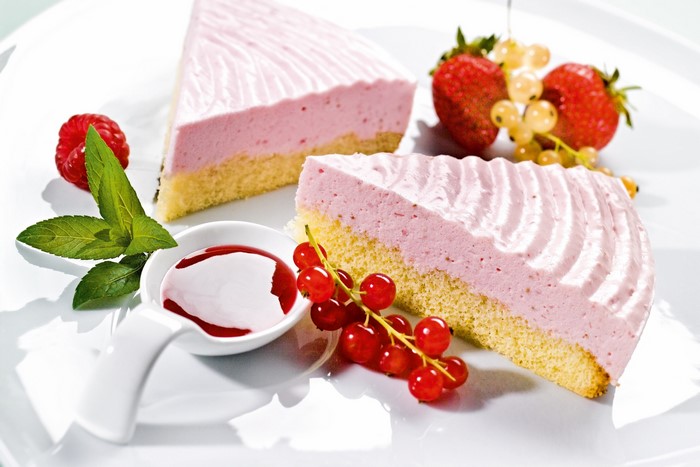 Slices of strawberry mousse cake with berries and sauce