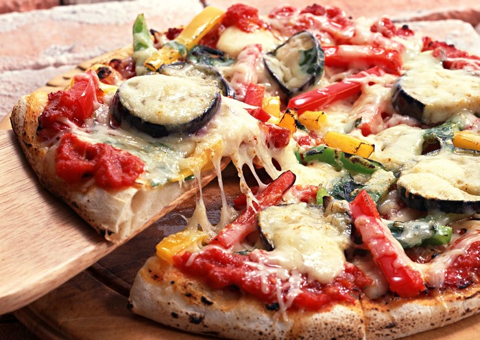 Vegetable pizza with melted cheese being served