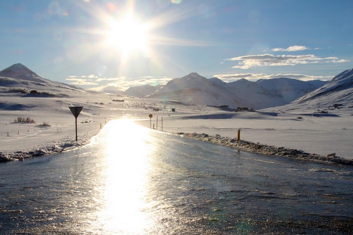 Sunlit icy road through snowy mountains in Iceland