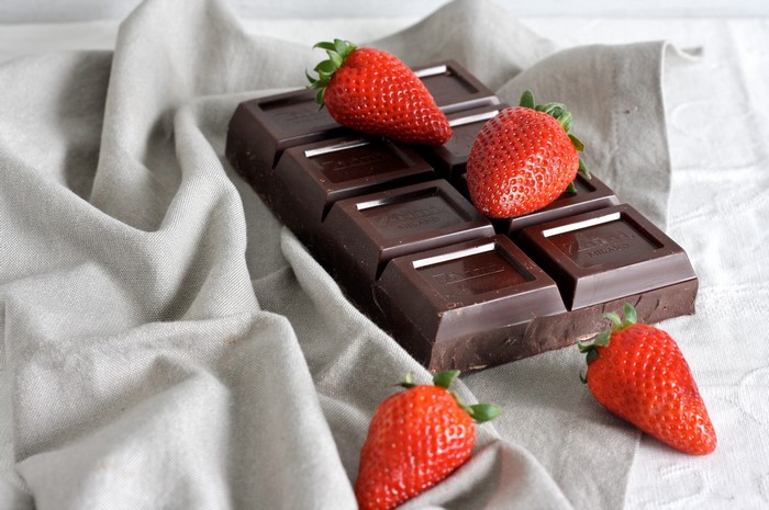 Dark chocolate bar with strawberries on a linen cloth
