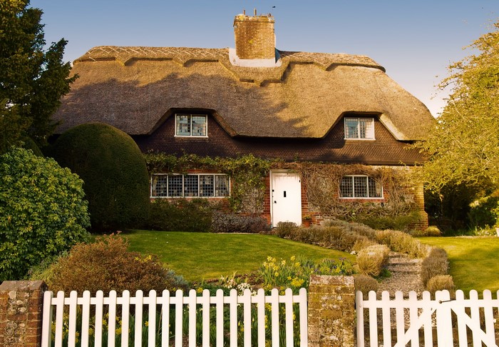 Thatched roof cottage in Hampshire, England with white picket fence
