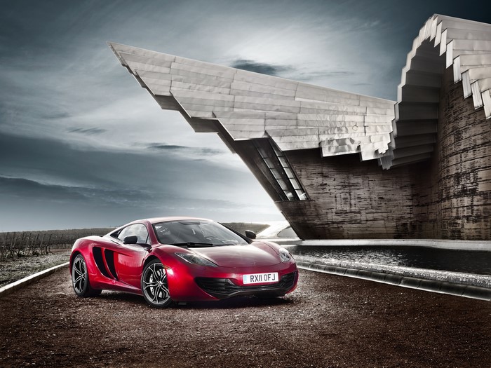 Red McLaren MP4-12C parked near modern architecture
