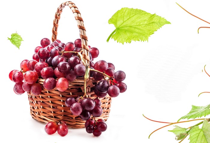 Red grapes in a wicker basket with green leaves