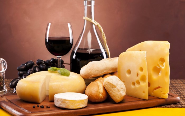 Cheese, wine, bread, and grapes on a wooden board