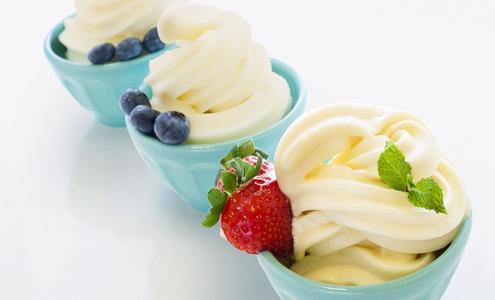 Three bowls of soft serve ice cream with fruit toppings