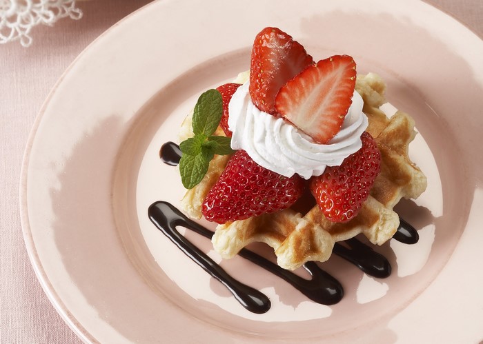 Waffle with strawberries, whipped cream, and chocolate sauce