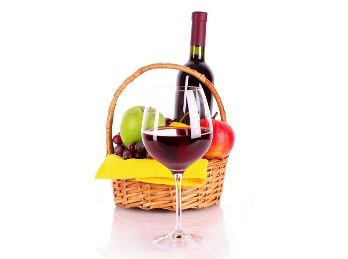Wine bottle and fruit in wicker basket with wine glass