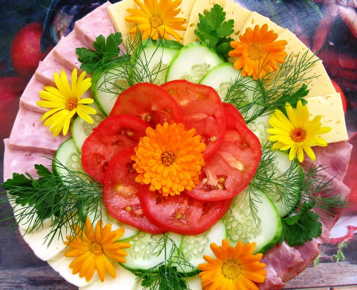 Platter of sliced meats, cheese, tomatoes, cucumbers, and flowers
