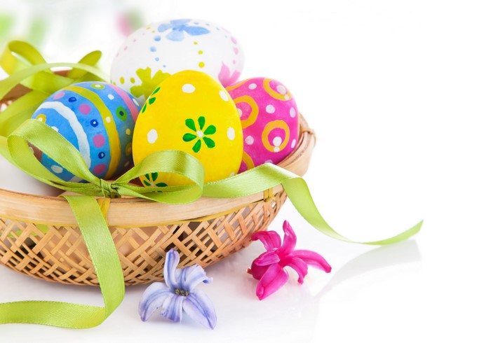 Easter eggs in a wicker basket with ribbon and flowers