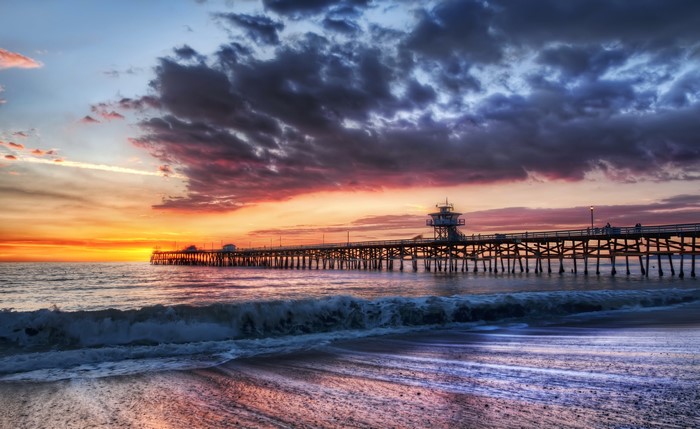 Sunset over a pier in California with waves