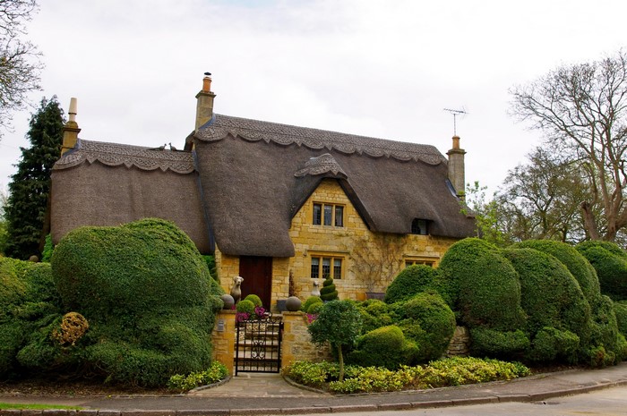 Thatched cottage with topiary garden in England