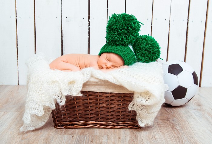 Newborn baby in a basket with a soccer ball