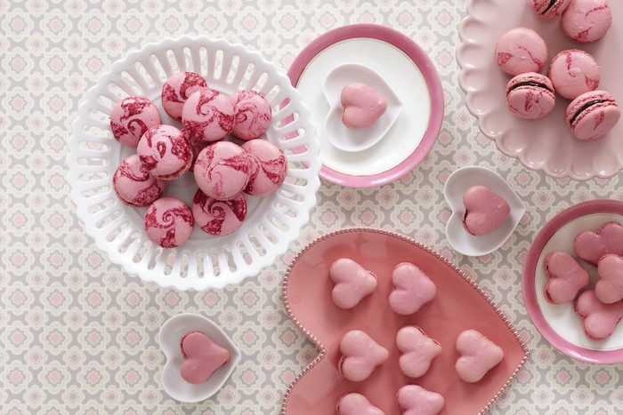 Pink heart-shaped and swirled macarons on plates