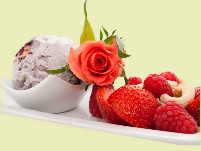 Ice cream with strawberries, raspberries, cashews, and a rose