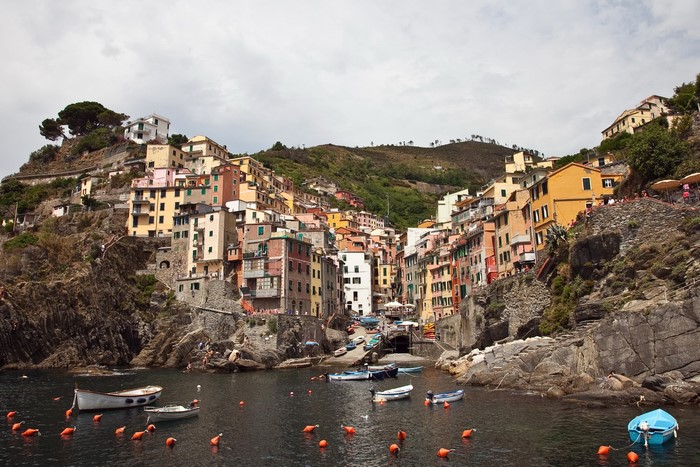 Riomaggiore, Italy colorful houses on a rocky coast with boats