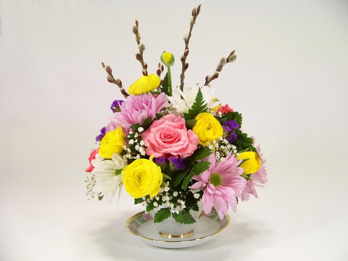 Teacup floral arrangement with roses and ranunculus